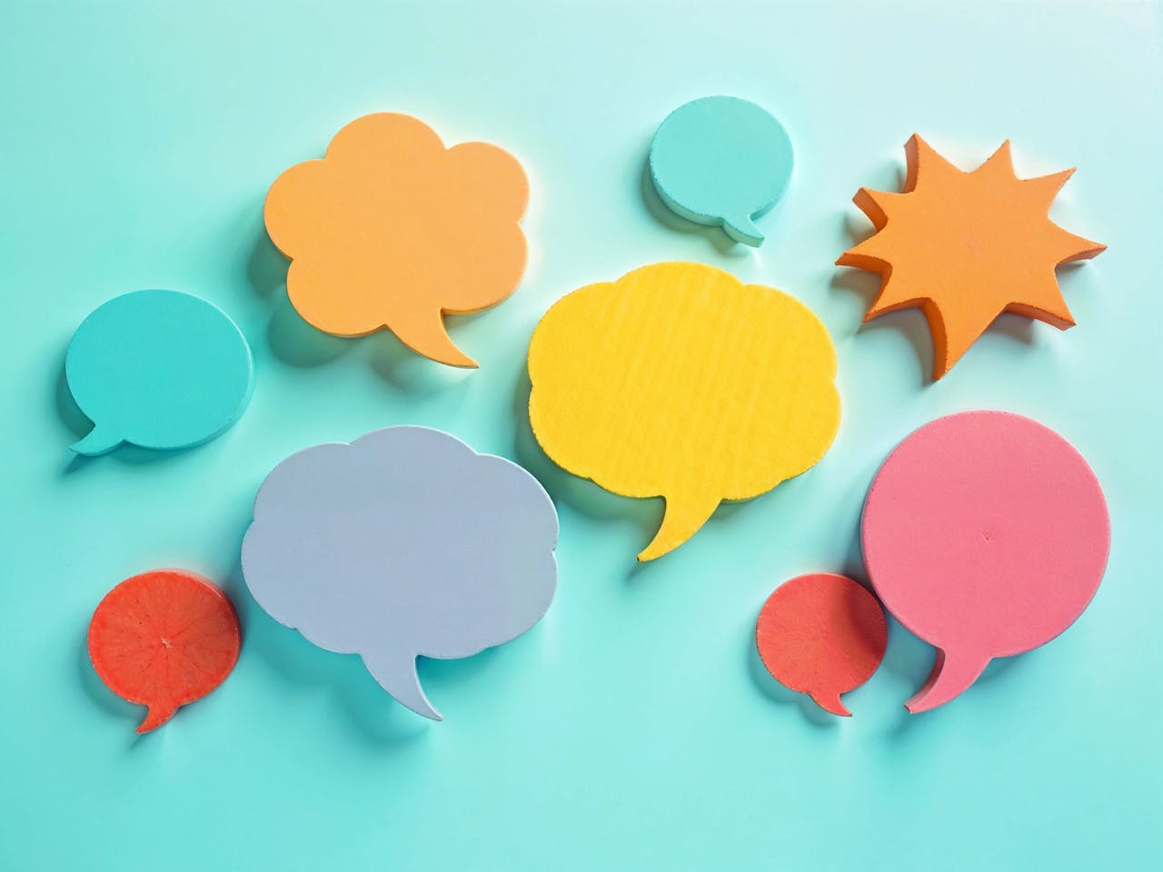 Vibrant paper cut speech bubbles on a turquoise background, perfect for communication themes.