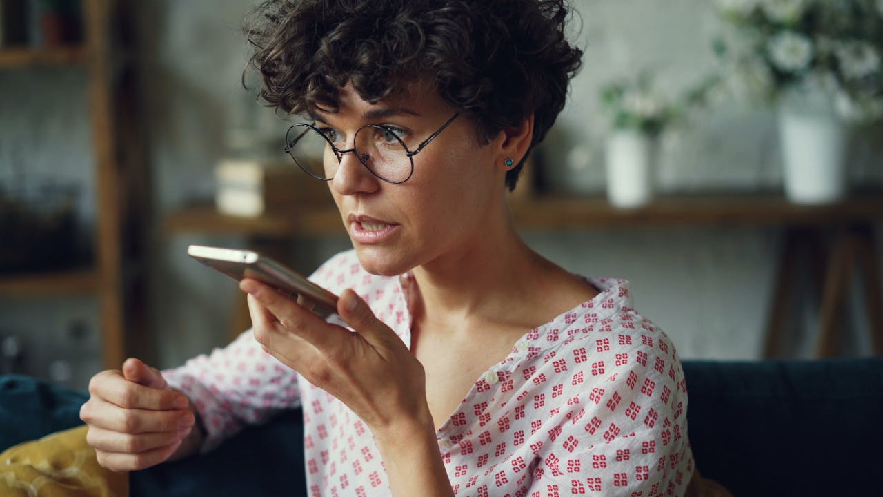Casual woman using voice command on smartphone at home.